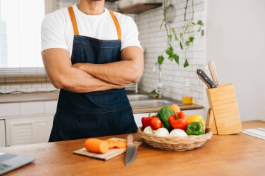 Genç adam ellerini kapat ve sağlıklı bir salata hazırla. Mutfak tezgahındaki kesme tahtasında sebze doğramak..
