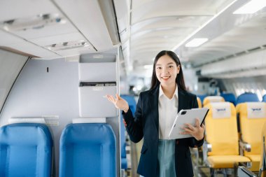 Çekici Asyalı kadın uçak yolcusu tablet bilgisayarda çalışıyor kablosuz bağlantıyı kullanarak alanı taklit ediyor. Stil içinde seyahat et, zarafetle çalış.