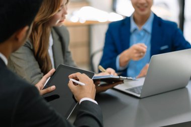 Asyalı iş adamlarından oluşan bir grup modern ofiste çalışmayı tartışıyor.