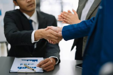 Asyalı iş adamlarından oluşan bir grup modern ofiste çalışmayı tartışıyor.