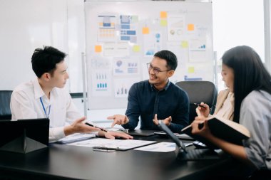 Ofiste yeni bir proje üzerinde çalışırken mutlu iş adamları. Ofiste bir dizüstü bilgisayar ve tablet kullanan bir grup iş adamı.