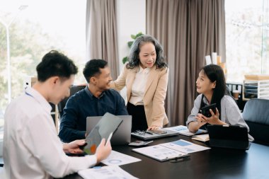Ofiste yeni bir proje üzerinde çalışırken mutlu iş adamları. Ofiste bir dizüstü bilgisayar ve tablet kullanan bir grup iş adamı.