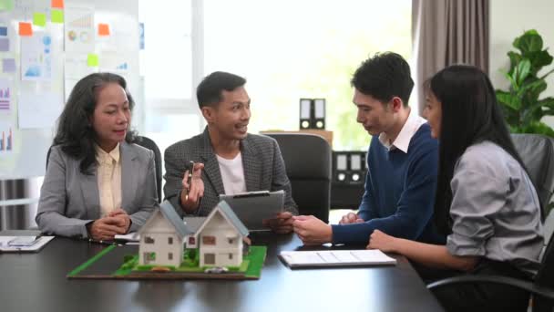 家族のカップルは 不動産業者や住宅所有者とのリースミーティングにサインし 最初の住宅ローンと住宅ローンの所有権の概念を購入します オフィスで — ストック動画