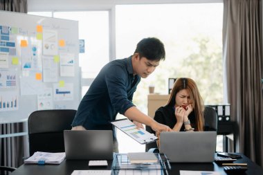 Modern ofiste dizüstü bilgisayarlarla çalışan Asyalı iş adamları