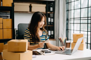 Başlangıçta küçük işletme KOBİ 'si, girişimci sahibi kadın paket ürün kutusu hazırlamak için online alışveriş siparişi alıyor ve kontrol ediyor. 