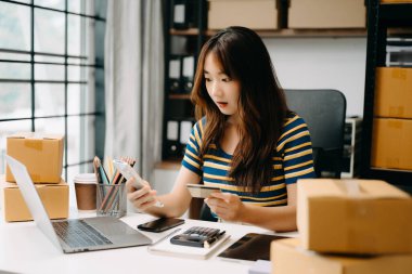 Başlangıçta küçük işletme KOBİ 'si, girişimci sahibi kadın paket ürün kutusu hazırlamak için online alışveriş siparişi alıyor ve kontrol ediyor. 