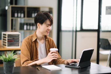 Asyalı işadamı ofisteki dijital tablet çalışmasından memnun ve memnun.