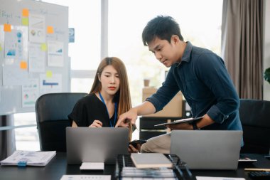 Modern ofiste dizüstü bilgisayarlarla çalışan Asyalı iş adamları