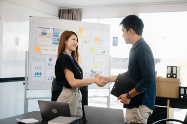 Modern ofiste dizüstü bilgisayarlarla çalışan Asyalı iş adamları