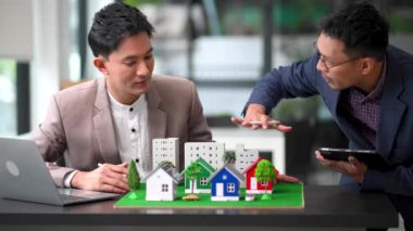 Mülk sektörünü dengelemek. Emlakçı ev tasarımını ve satın alma anlaşmasını görmek için ev tarzını anlatıyor. Modern ofiste model ev