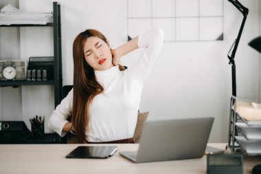 Ofis masasında uzun bir gün geçirdikten sonra boynu ağrıyan Asyalı genç işkadını ofis çalışanı. ofis sendromu kavramı