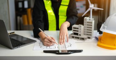 Modern ofisteki inşaat sahasında mimari projeyle büyük çizimlere yansıyan yaratıcı mimarlar