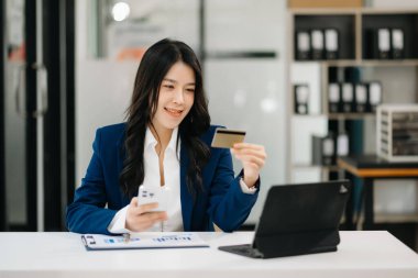 Asyalı Kadın mobil ödemeler için akıllı telefon kullanıyor online alışveriş, omni kanalı, masada oturuyor, sanal simge grafik arayüzü ekranı