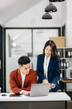 Nazik yönetici yönetici iş çözümlerini modern ofiste Asyalı kadın pazarlama yöneticisiyle paylaşır ve tartışır.