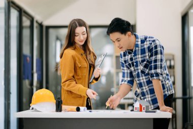 Çalışma ve tablet hakkında konuşan iki meslektaşım, ofisteki inşaat alanında mimari projeli dizüstü bilgisayar.