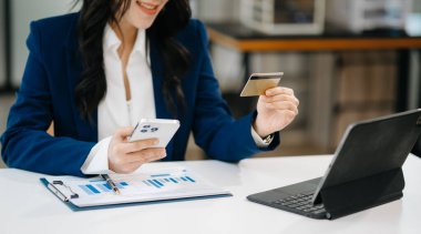 Asyalı Kadın mobil ödemeler için akıllı telefon kullanıyor online alışveriş, omni kanalı, masada oturuyor, sanal simge grafik arayüzü ekranı
