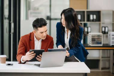Nazik yönetici yönetici iş çözümlerini modern ofiste Asyalı kadın pazarlama yöneticisiyle paylaşır ve tartışır.