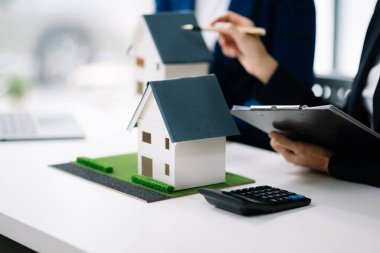 Emlak komisyoncusu, emlak kredisi teklifiyle ilgili sözleşme imzalama anlaşmasını, ev modelini sunar ve müşteriye danışmanlık yapar.