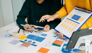  UX geliştiricisi ve ui tasarımcısı modern ofiste müşteri breif ve renk kodu ile mobil uygulama arayüzü kablo tasarımı hakkında beyin fırtınası yapıyorlar.