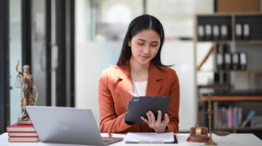 Genç Asyalı kadın avukat ofiste tablet bilgisayar kullanıyor..