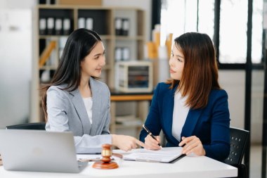 Asian business team of lawyers discussing contract papers sitting at the table. Concepts of law, advice, legal services. at office clipart