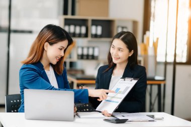 Asyalı iş arkadaşı sunar ve yeni projeyi açıklar. Takım çalışması, finansal pazarlama ekibi, modern ofis odasında otururken. 