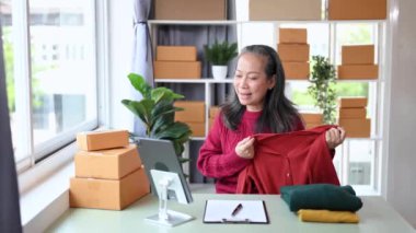 Moda blogcusu konsepti, üst düzey Asyalı kadın ev ofisinde video yayınında kıyafet satıyor. Başlangıçta küçük işletme, KOBİ kavramı