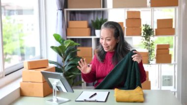 Moda blogcusu konsepti, üst düzey Asyalı kadın ev ofisinde video yayınında kıyafet satıyor. Başlangıçta küçük işletme, KOBİ kavramı