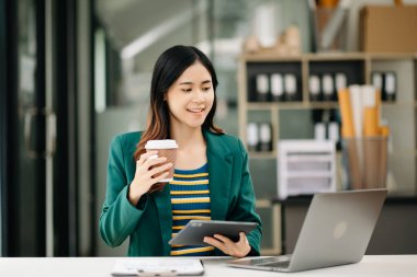 Genç ve güzel bir kadın laptopta çalışırken beyaz masadaki modern ofiste çalışıyor.
