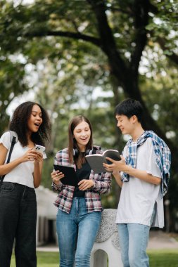 Öğrenciler birlikte kampüs parkını inceliyorlar. Tutma kitabı, tablet ve akıllı telefon 