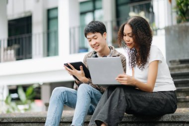 Kampüs parkındaki aletleri kullanarak birlikte okuyan genç üniversite öğrencileri.