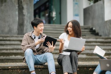 Kampüs parkındaki aletleri kullanarak birlikte okuyan genç üniversite öğrencileri.