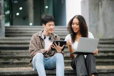 Kampüs parkındaki aletleri kullanarak birlikte okuyan genç üniversite öğrencileri.