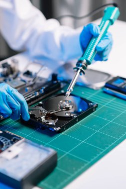  Teknisyenin masasında sabit disk ve bir bilgisayar ana kartı var. Veri, donanım ve bilgi teknolojisi kavramı. mavi ton