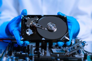  Teknisyenin masasında sabit disk ve bir bilgisayar ana kartı var. Veri, donanım ve bilgi teknolojisi kavramı. mavi ton