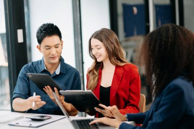 Ofiste yeni bir proje üzerinde çalışırken mutlu iş adamları. Ofiste bir dizüstü bilgisayar ve tablet kullanan bir grup iş adamı