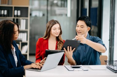 Ofiste yeni bir proje üzerinde çalışırken mutlu iş adamları. Ofiste bir dizüstü bilgisayar ve tablet kullanan bir grup iş adamı