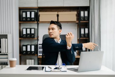 Ofis masasında uzun bir gün geçirdikten sonra boynu ağrıyan genç Asyalı iş adamı. ofis sendromu kavramı