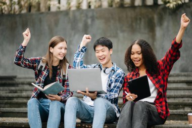 Mutlu öğrenciler merdivenlerde birlikte çalışıyorlar. Kitap okumak, dizüstü bilgisayar, tablet ve merdivenlerde otururken iletişim kurmak. 
