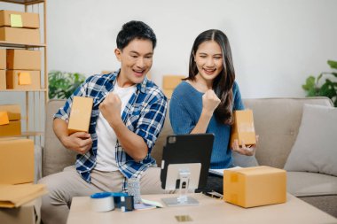 Giysilerini kameranın önünde gösteren iki Asyalı blogcu onun dükkanında canlı video kaydı yapıyor. Online Alışveriş Arabası kavramı. Evdeki kanepede.