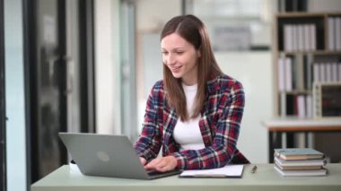Modern ofiste dizüstü bilgisayarla çalışan Kafkasyalı mutlu iş kadını 