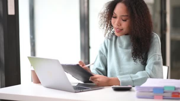 快乐的非洲女商人在办公室使用笔记本电脑 并在平板电脑上记笔记 — 图库视频影像