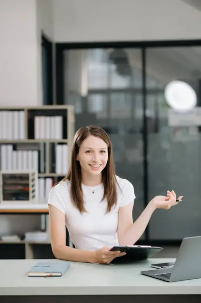 Confident business expert attractive smiling young woman holding digital tablet  on desk in creative office