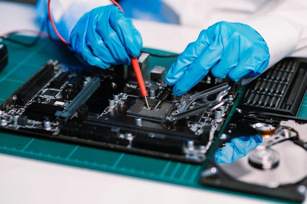 The technician is putting the CPU on the socket of the computer motherboard. electronic engineering electronic repair, electronics measuring and testing, repair in workshop