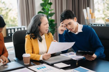 Asyalı iş adamları modern ofiste çalışma sürecini tartışıyor