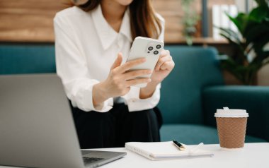 Ofiste çalışan ve akıllı telefon ve dizüstü bilgisayar kullanan bir iş kadını. 