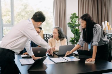 Asyalı iş adamları modern ofiste çalışma sürecini tartışıyor