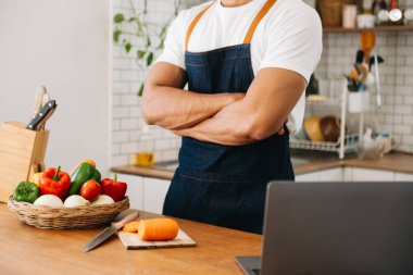 Genç adam ellerini kapat ve sağlıklı bir salata hazırla. Mutfak tezgahındaki kesme tahtasındaki domatesleri doğramak.