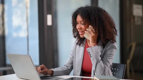 Dizüstü Bilgisayarla Çalışan Afrikalı Kadını Ofiste Akıllı Telefondan Konuşuyor — Stok video