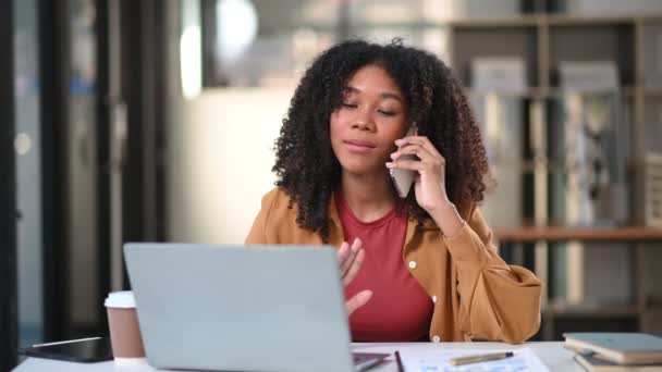 Dizüstü Bilgisayarla Çalışan Afrikalı Kadını Ofiste Akıllı Telefondan Konuşuyor — Stok video